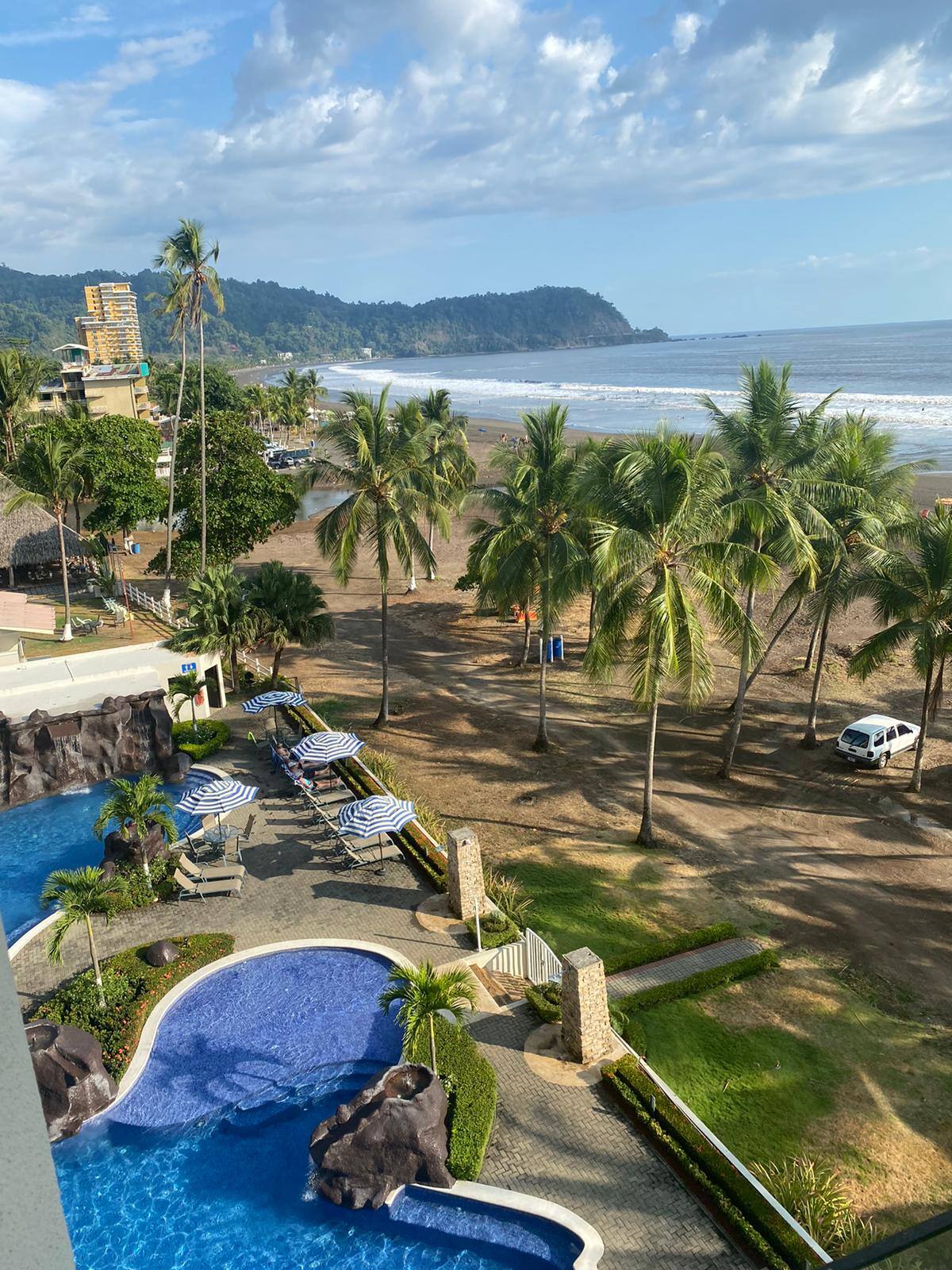Fifth-floor view of the pool, palm trees and Jaco Beach